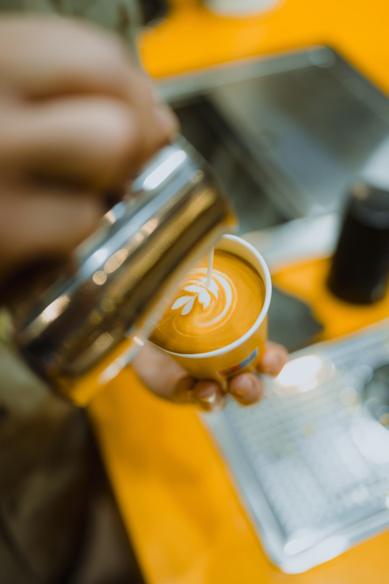 Barista schenkt latte art in een Dimello-beker